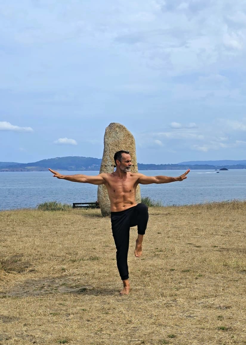 Fernando practicando una postura de artes marciales al aire libre junto al mar